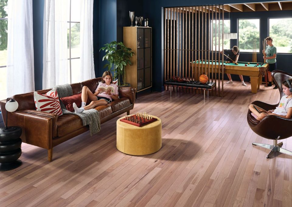 Family room with children lounging and playing pool; solid hickory hardwood floors; choosing the best hardwood for your family.