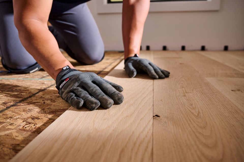 Man installing unfinished hardwood in a room