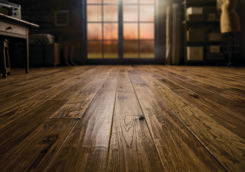 Close up of a hardwood floor with French doors in the background at sunset