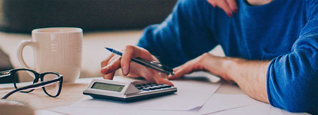 man sitting at a desk with pen and calculator to plan out costs for wood flooring